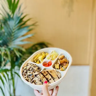 a person holding a bowl of food in front of a hello sign