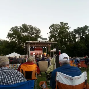 a crowd of people sitting in lawn chairs in front of a stage