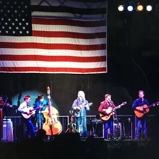  a band on stage with an american flag in the background