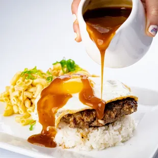 a person pouring gravy over a plate of food
