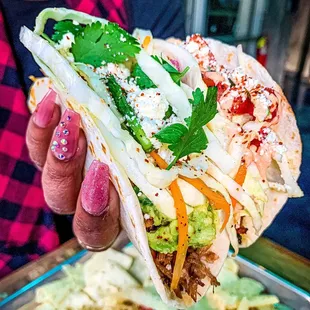 a person holding a taco with toppings