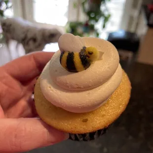 a hand holding a cupcake with a bee on it