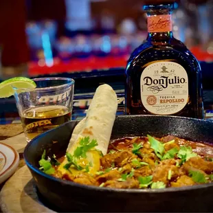 a skillet of mexican food and a bottle of tequila