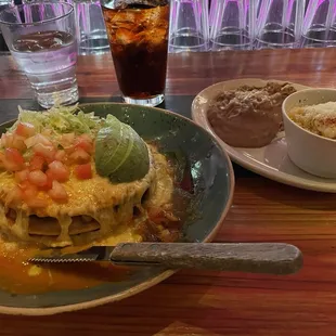 Stacked carnitas enchilada with refried beans and street corn