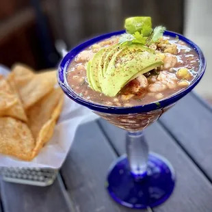 a bowl of soup with avocado and chips