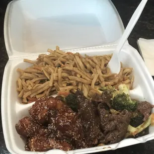 a take out container with noodles, beef and broccoli