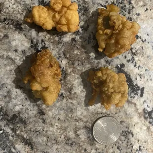three pieces of fried chicken next to a quarter