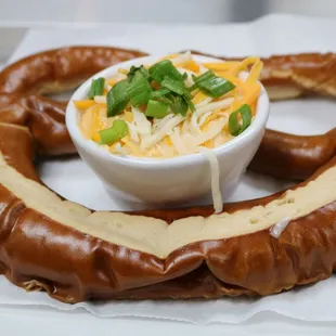 a pretzel with cheese and green onions