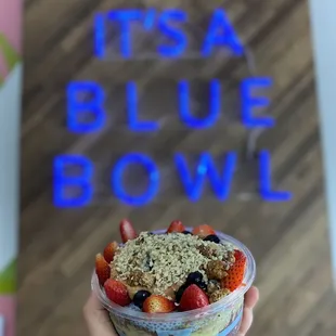 a hand holding a bowl of fruit