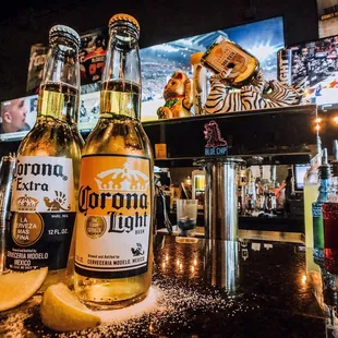 two corona beer bottles on a bar