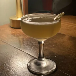 a cocktail in a coupe glass on a wooden table