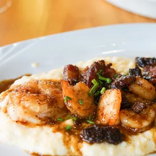 a plate of mashed potatoes with shrimp and mushrooms