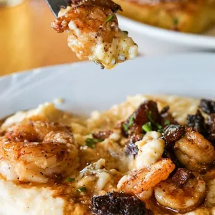 a fork lifting up a piece of shrimp over mashed potatoes