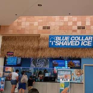 people standing in front of a blue collar shaved ice