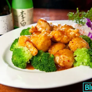 a plate of chicken and broccoli with a bottle of wine