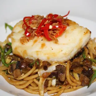 The Miso Chilean Seabass is made with Pan Fried Noodles, Vegetables, Crispy Shallot, Shiitake Mushrooms, Fresno Chile, and Miso Sauce.