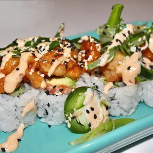 The 'Movie Night Roll' is made with Spicy Salmon Tartar, Avocado, Cucumber, Popcorn Shrimp, Thai Butter, Jalapeño, and Cilantro.