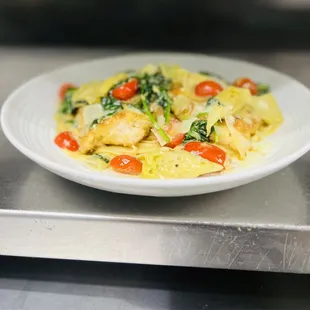 a plate of pasta with chicken and tomatoes