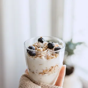 a hand holding a glass of yogurt