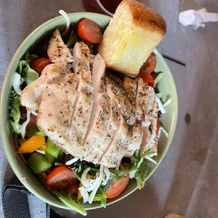 a salad with chicken, tomatoes, lettuce, and bread