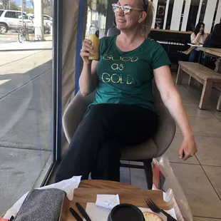 a woman sitting in a chair and holding a glass of beer