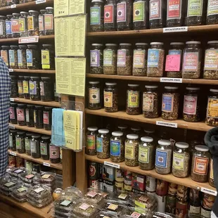 a man standing in front of a shelf of teas