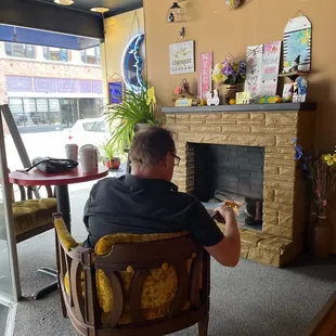 a man sitting in a chair in front of a fireplace