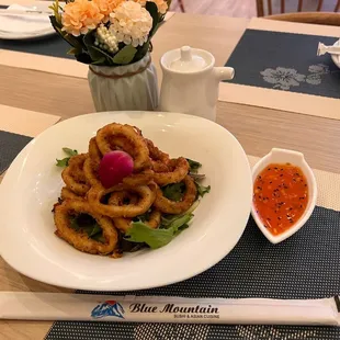 a plate of onion rings and a bowl of dipping sauce