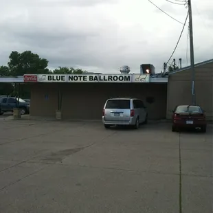 two cars parked in front of a blue note ballroom