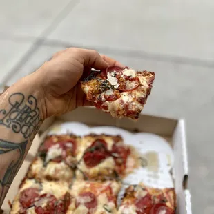 a hand holding a slice of pizza