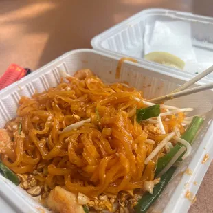 a take out container with noodles and chopsticks