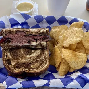 Pastrami sandwich with smoked provolone on toasted marble rye bread with Mrs. Vickys jalapeño kettle chips.