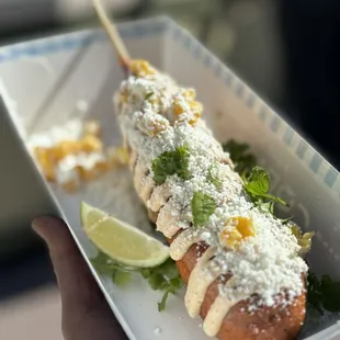 a person holding a plate of corn dogs