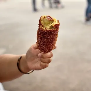 a person holding a corn dog