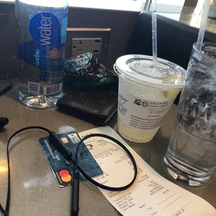 a bottle of water, glasses, a credit card, and a drink on a table