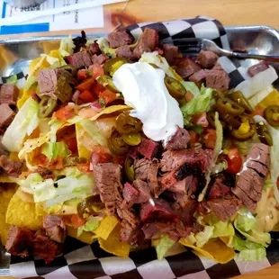 Nachos!   Tortilla chips layered with your choice of meat, queso, lettuce, pico, pickled jalapenos and sour cream. (Pic-Smoked Beef Brisket)