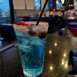 a blue cocktail with a straw and garnish garnish