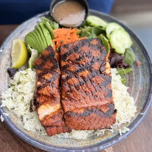 Bluewater plate with salmon blackened, sides of rice and a salad with avocado