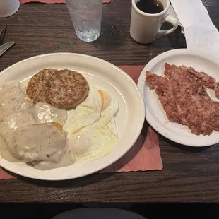 Biscuits and sausage patties with sausage gravy and two over easy eggs and corned beef hash.