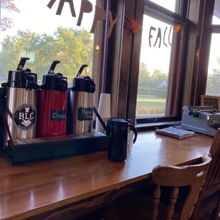 a table with a coffee maker and cups on it