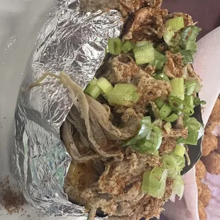 Baked potato loaded up with pulled pork, cheese, butter, sour cream and green onions.