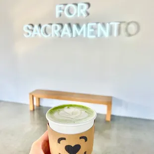 a hand holding a cup of matcha latte