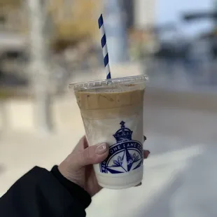 a hand holding a cup of iced coffee