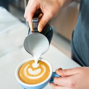 a person pouring milk into a cup of coffee
