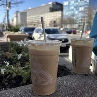 two cups of iced coffee on a sidewalk