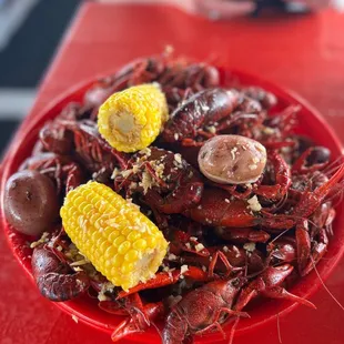 a plate of crawfish, corn, and potatoes