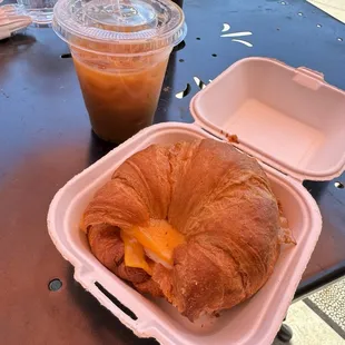 Bacon egg and cheese on a croissant with an onion ced Americano