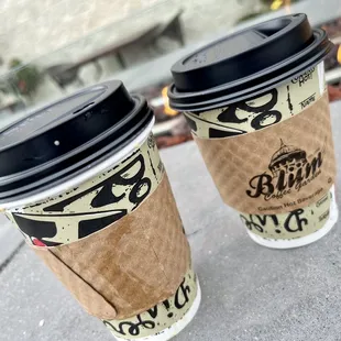 two coffee cups on a sidewalk