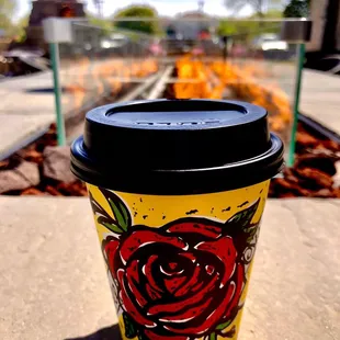 a coffee cup with a red rose painted on it