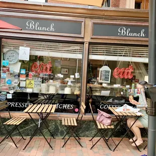 a woman sitting on a bench in front of a restaurant